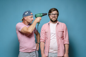 Neighbor makes repairs. Serious man put an electric screwdriver to the unfortunate male head....