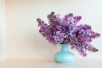 bouquet of purple lilacs on a light background in a vase