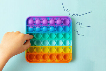 Child playing with rainbow pop it,pressing the bubbles with his fingers,top view.Image of clicks on the sidesNew antistress toy for children and adult.Copy space for text or design.