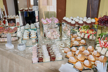 Festive sweet table. Candy bar with cakes, pastries, mousses and fruit.