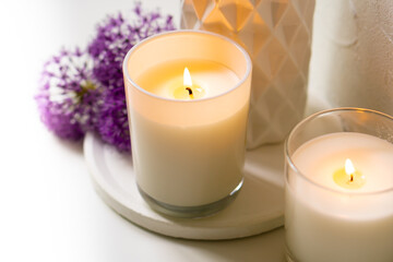 Fototapeta na wymiar Burning candle and violet allium flowers on white tray