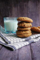 stack of whole meal cookies and glass of milk on wooden background