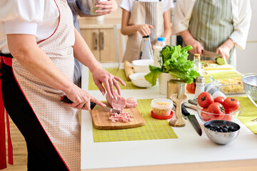 Close-up photo of table with female hands cutting ingredients for dinner, preparing meal, using cutting board. Food, dinner, meal, cook concept