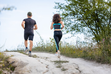 Back view of couple or friends running outdoors