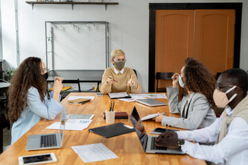 Two businesswomen in masks discussing new business perspectives in working environment