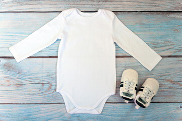 Top view white baby bodysuit with long sleeve on wooden background. Copy space for lettering or...