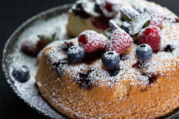 Fruit pie with powdered sugar and cinnamon on white plate, home baked closeup