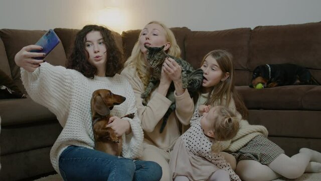 Mom, daughters taking photos with animals and sitting on couch at home living room rbbro.