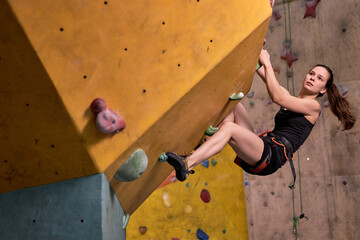 Young Woman Climbs Up An Indoors Rock Wall, Athlete Female Clearly Determined To Make It To The...