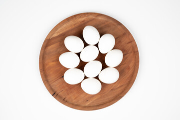 White eggs on a wooden plate on a white background. Organic eggs.