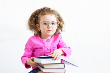 serious, brooding, cute smart little girl in funny big glasses reading a stack of paper books. Training, education, knowledge. back to school. child holding textbooks and doing homework. copy space