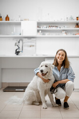 A portrait of young female owner with big white dog waiting for the veterinarian in veterinary clinic. Pet care concept