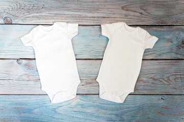 Layout Flat Put on a two white baby bodysuit on a wooden background. Layout for design and...