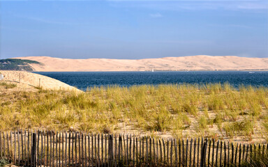 Dune and a barrier protecting the dunes at Cap-Ferret with the Dune of Pilat in the background. Commune in the Gironde department in southwestern France