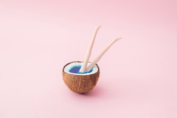 Half a coconut with blue water and plastic doll legs protruding from the coconut.