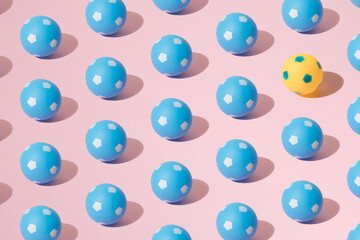 Arranged blue and yellow soccer ball on a pink background. Minimum pattern.