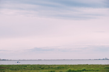 A man on a kayak in the distance on the horizon between two shores