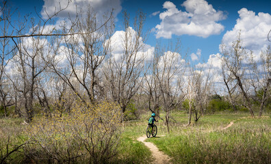 Medicine Hat Alberta Canada, May 14 2021: A young boy mountain biking along a dirt trail in an urban park near the town of Redcliff Alberta.