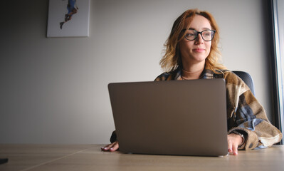 Office worker. Woman using laptop. Freelancer. Communicates on internet. Business woman.