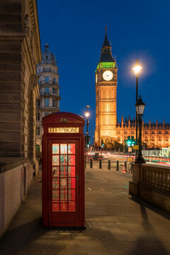 Red telephone box in front of Big Ben at night, London, United Kingdom