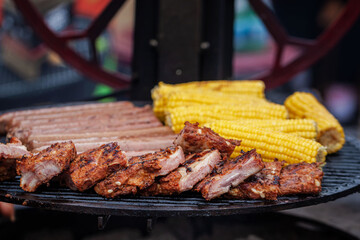 Mix of Rack of pork ribs, Beef sausages and corn on the cobs on the grill