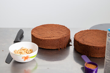 Front view of two thick layers of baked chocolate sponge cake on metal table