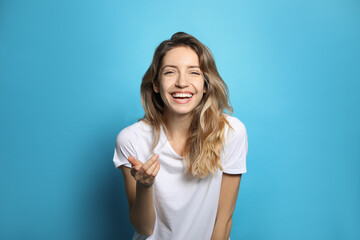 Cheerful young woman laughing on light blue background