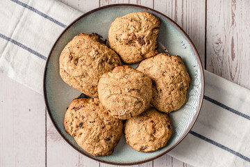 Close up top view on crunchy oatmeal chip cookies fresh baked biscuits with chocolate and cocoa in a plate on the table - homemade food concept copy space