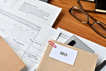 There is card with the word SEO on it with dummy paper of design of web systems.