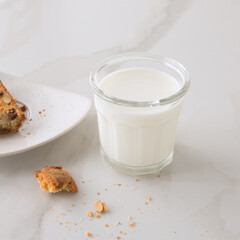 a glass of milk and cantucci cookies on a light marble table
