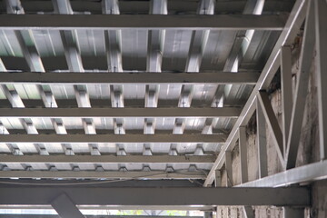 Fototapeta premium Bottom side of a metal roof and construction frame made of profile metals and white color.