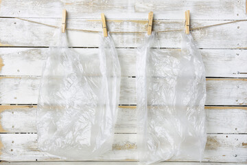 An image of recycled clear plastic bags hanging by cloths pin on a white board. 