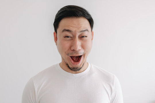 Funny grin smile face of Asian man in white t-shirt isolated on white wall.