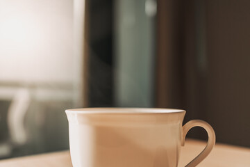 Hot cup of drink on the table in sun light of calm and warm morning.