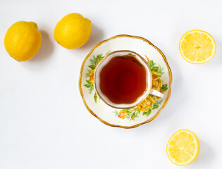 Floral teacup with tea and saucer, lemons on the background