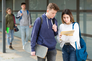 Teenage boy and girl discuss homework after college lessons on sunny spring day © JackF