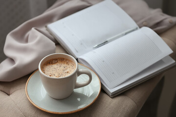 Cup of aromatic coffee and notebook on bench indoors
