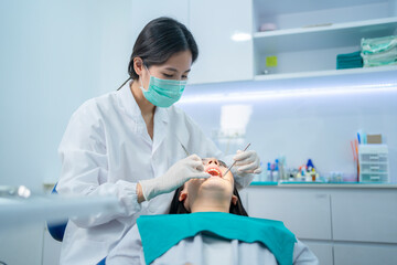 Asian dentist wearing face mask, providing dental service in clinic.	