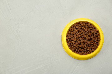 Dry food in pet bowl on grey background, top view. Space for text