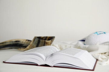 Open Torah, shofar and tallit on white wooden table, space for text. Rosh Hashanah celebration