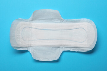 Sanitary napkin on light blue background, top view. Gynecology concept
