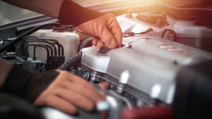 Auto mechanic working in garage. Repair service.Turn on and fill up the engine oil.