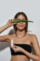 Smiling young asian girl hiding behind aloe leaf