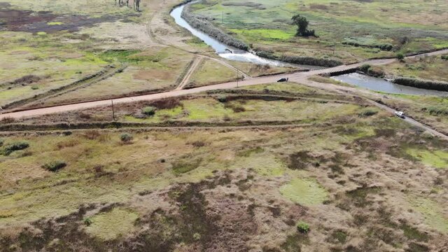 Aerial drone shot of the river flowing under a remote gravel road bridge in the Johannesburg, South Africa. The Klipriver making its way to the Vaal River