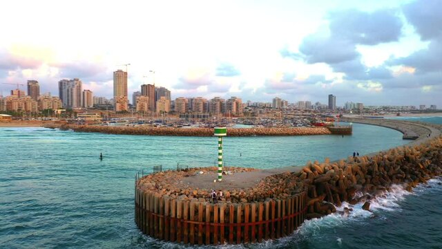 Aerial Panning Shot Of Groyne With Harbor And City In Background, Drone Flying Over Sea - Ashdod, Israel