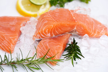 Fresh salmon fish on ice, Raw salmon filet with lemon rosemary herbs and spices on white plate