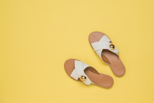 Top view of yellow leather sandals on a yellow background.