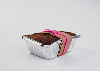 Pan de zanahoria con nuez recién horneado en un recipiente de metal con un lazo rosa sobre un fondo blanco