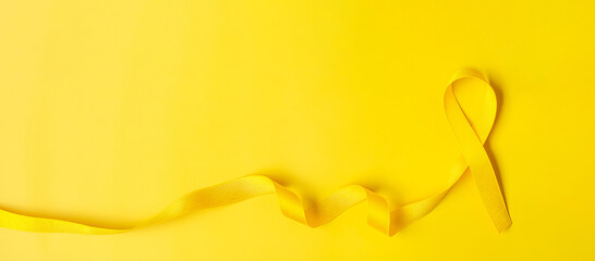 Yellow Ribbon on yellow background for supporting people living and illness. July Sarcoma cancer, Suicide prevention day, Childhood Cancer Awareness month concept - obrazy, fototapety, plakaty