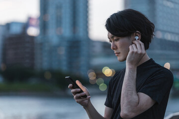 屋外で音楽を聞きながらランニングの準備をする若い男性